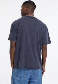 Czarnoszary krótki rękaw t-shirt z bawełny, w luźnym kroju, z okrągłym dekoltem i gładką fakturą. Prosty design, bez widocznych wzorów.