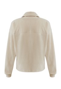 Beige jacka med krage och långa ärmar, mjuk i texturen och avslappnad i passformen. Har en enfärgad baksida med en ren söm över axlarna.