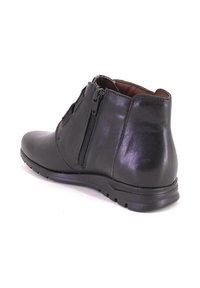 Bota de cuero negro hasta el tobillo con cremallera lateral, punta redondeada y suela texturizada. Acabado liso con tacón resistente y detalle sutil en el forro interior.