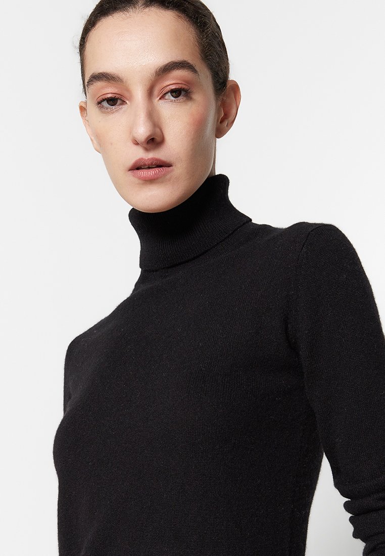 Zwarte coltrui gemaakt van zachte brei stof. Strakke pasvorm met lange mouwen en een hoge kraag. Eenvoudige, naadloze constructie.
