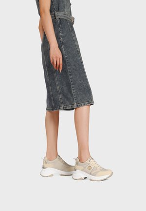 Scarpe da ginnastica beige con tessuto strutturato e pannelli in mesh, dotate di una suola bianca spessa e accenti grigio chiaro, abbinate a un vestito di denim.