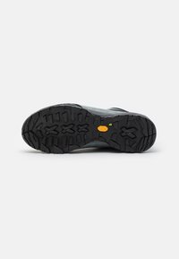 Scarpa da esterno grigia con una suola in gomma nera testurizzata, dotata di un motivo di battistrada distintivo e un dettaglio con logo sul lato.