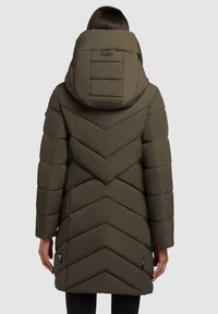 Khaki puffermantel med ett chevronmönster, stor huva och dragkedjefickor. Tyget har en slät yta och är vadderat.