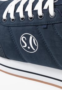 Námořnické plátěné sneakers s bílými tkaničkami, gumovou podrážkou a vyšitým logem, s bočním šitím a klasickým nízkým profilem.