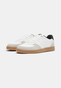 Weiße Sneakers mit grauen Wildleder-Akzenten, schwarzer Ferse und Gummisohle. Verfügt über eine perforierte Zehenbox und ein klassisches Schnürdesign.