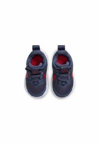 Zapatos deportivos en azul marino con un upper texturizado, detalles en rosa y suelas de goma. Presentan un diseño con cordones y una lengüeta para facilitar el calzado.