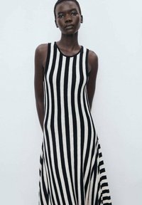 Black and white striped sleeveless dress with a fitted top and flared bottom, made from a soft, textured fabric. Simple round neckline.