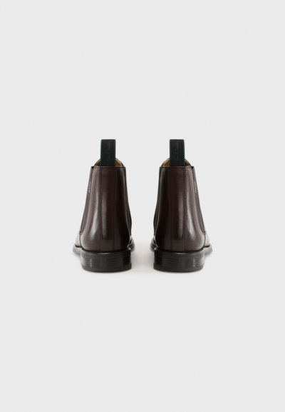 Bottines Chelsea en cuir marron avec des panneaux latéraux élastiques et des tirants contrastants verts, présentant une finition lisse et un design à bout rond.