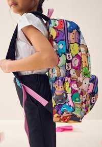 Bunter Rucksack mit einer Vielzahl von Cartoonfiguren, aus weichem Stoff gefertigt. Das Design umfasst zwei Reißverschlusstaschen und gepolsterte Tragegurte.