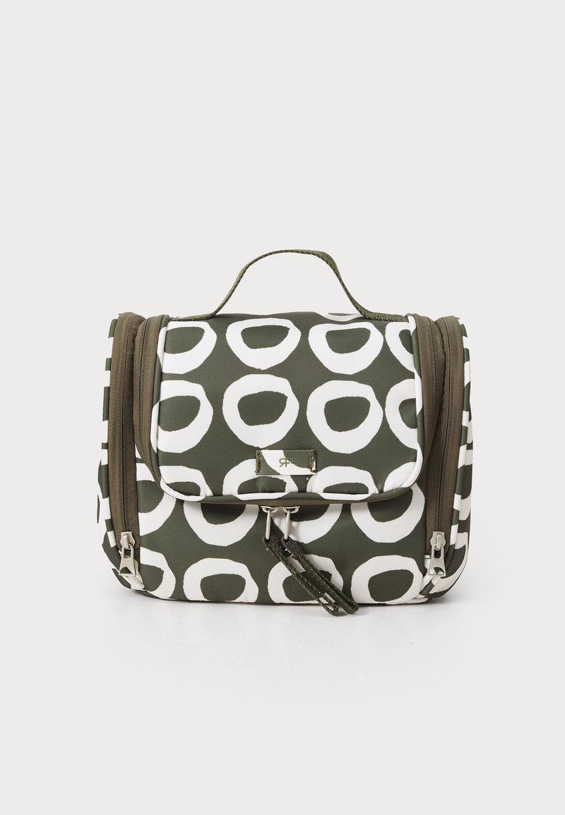 Green fabric bag featuring large white circular patterns, a top handle, two zippers, and a flap closure. Textured surface with contrasting accents.