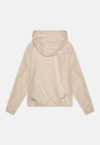 Veste légère beige en matériau lisse et résistant à l'eau. Dotée d'une capuche, de poignets élastiques et d'un ourlet froncé. Design minimaliste.