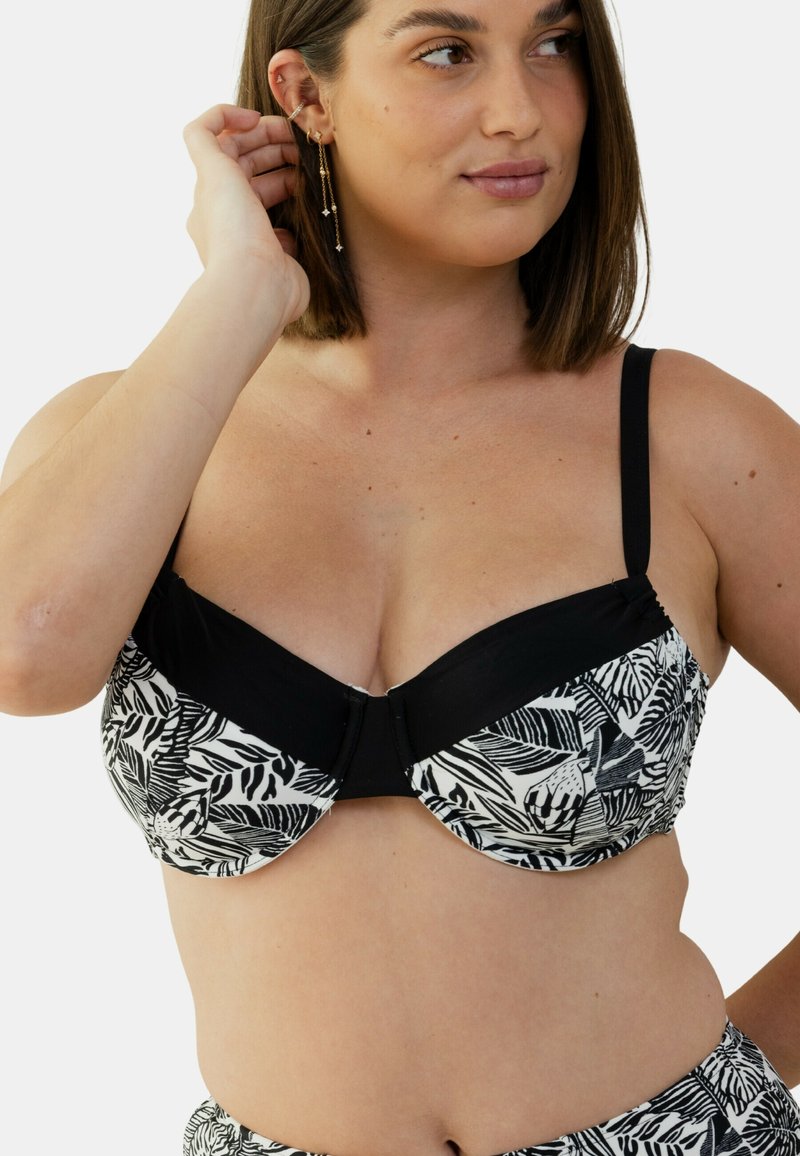 Soutien-gorge noir et blanc à motifs avec une forme structurée, incorporant des designs floraux sur les bonnets et une bande noire en dessous.