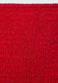 Tissu rouge avec une texture plissée et des volants horizontaux, créant de la profondeur et de la dimension sur toute sa surface.