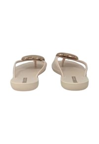 Infradito beige con suola piatta, caratterizzati da un accento metallico sulla cinghia del dito e una texture liscia. Le cinghie sono minimaliste e slanciate.