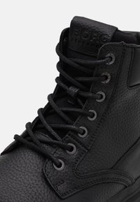 Stivale alla caviglia nero in pelle texturizzata, con occhielli in metallo, lacci piatti e linguetta imbottita impreziosita dalla scritta "BORG". Finitura opaca.