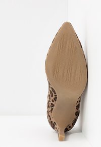 Chaussure à talon haut à imprimé léopard, bout pointu, texture en daim, semelle beige avec de légères rainures et talon fin effilé.