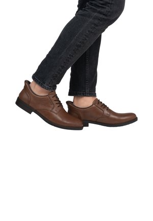 Braune Lederschuhe mit glatter Oberfläche, Schnürdesign, kontrastierenden strukturierten Akzenten und einer schwarzen Gummisohle, getragen mit dunklen Jeans.