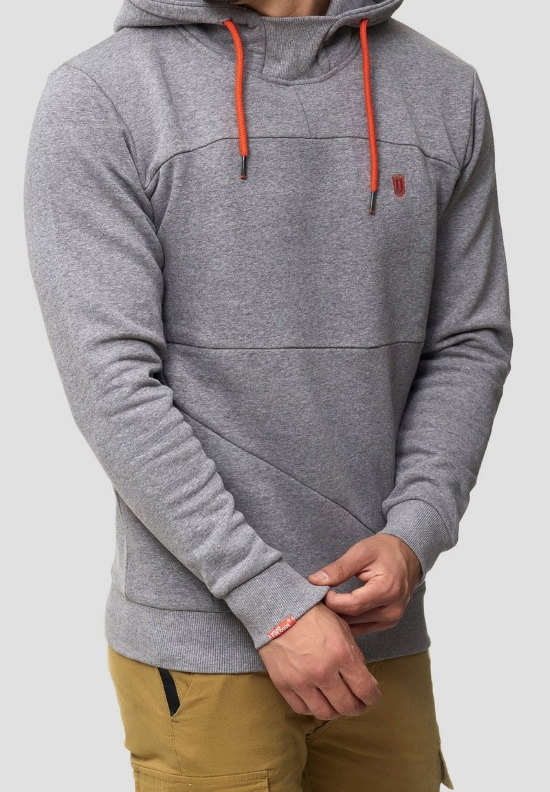Grijze hoodie met oranje trekkoorden, voorzien van een gestructureerd ontwerp en diagonale naadtoeslagen. Ribgebreide manchetten en zoom voor extra duurzaamheid.