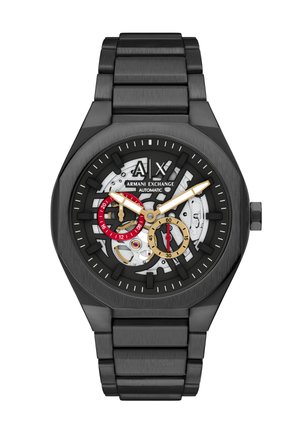 Reloj de pulsera automático negro Armani Exchange con esfera esqueleto, subesferas en dorado y rojo, manecillas de horas y minutos doradas, y brazalete de metal negro.