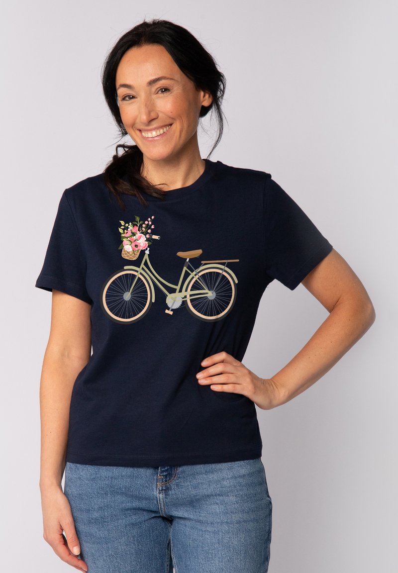 T-shirt bleu marine avec un graphique de bicyclette ; présente un vélo vert clair avec un panier de fleurs, des manches courtes et une coupe classique.