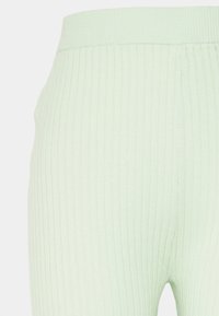 Leggings verde claro canelados com uma cintura elástica larga e uma textura suave, apresentando riscas verticais que criam um padrão distinto.