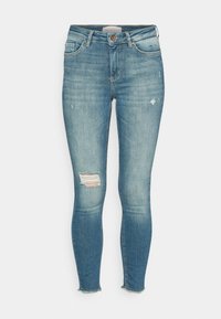 Jeans ajustados de color azul con un lavado desvanecido, presentan desgarros en las rodillas, dobladillo deshilachado y un diseño clásico de cinco bolsillos con botón de cierre.