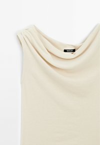 Top senza maniche color beige con collo a cappuccio, realizzato in tessuto morbido, con dettagli drappeggiati sulle spalle e un design semplice e pulito.