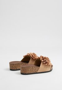 Sandalias de plataforma de ante beige con acentos florales, plantilla de corcho y suela de goma negra texturizada. Diseño de punta abierta, estilo casual.