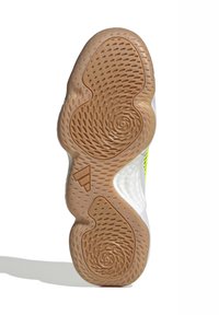 Suela de zapato de goma beige con patrones circulares y surcos; presenta un borde superior blanco con un brillante acento en amarillo neón.