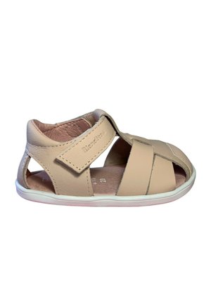 Sandalia beige de cuero para niño pequeño con tira ajustable de velcro y diseño de punta abierta sobre suela blanca de goma.