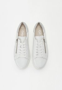 Vita syntetiska läder sneakers med silvriga accenter, med snörning och sidodragkedja, har en platt gummisula och minimalistisk design.