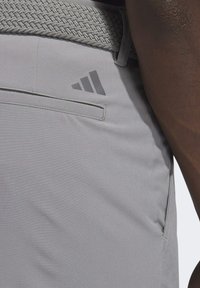Pantaloni atletici grigi con una cintura tessuta e strutturata, tasca laterale e un accento logo grigio scuro sull'anca sinistra.