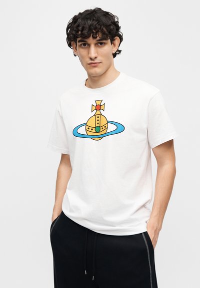 Άσπρο βαμβακερό μπλουζάκι με πολύχρωμο γραφικό ενός κίτρινου πλανήτη με δαχτυλίδια και κόκκινο και πράσινο σχέδιο, στρογγυλή λαιμόκοψη, κοντά μανίκια.