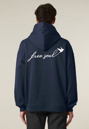 Marineblauwe hoodie met een losse pasvorm, voorzien van een witte cursieve tekst "free soul" en een kleine vogelafbeelding op de achterkant.