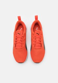 Scarpe atletiche rosse in rete con accenti neri, punta rotonda e chiusura con lacci. Presentano un tassello sul tallone e una suola in gomma bianca con battistrada testurizzato.