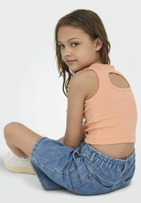 Top court en côtelé pêche avec un détail découpé au dos, associé à un short en denim taille haute avec une taille élastique et des poches avant.