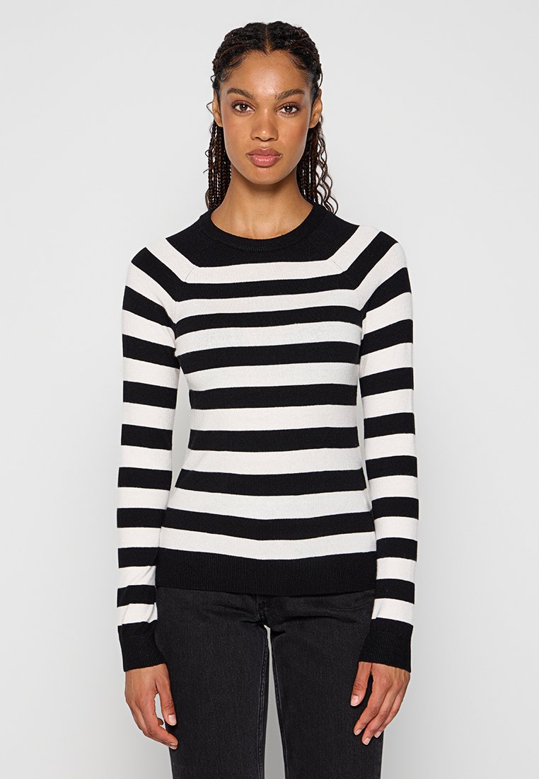 Pull à rayures noir et blanc avec un col rond et des manches longues. Présente des poignets et un ourlet côtelés, en tissu tricoté texturé.