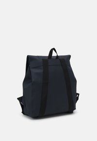 Sac à dos bleu foncé en tissu avec une texture lisse, doté de deux bretelles noires, d'une poignée supérieure et d'une fermeture à rabat replié.
