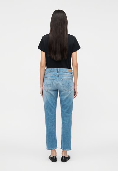 Ljusblå denimjeans med rak benpassform, blekta områden och sydda bakfickor. Matchas med en svart t-shirt med korta ärmar.