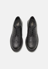 Čierne kožené topánky s brogue detailmi, šnurovací dizajn a textúrovaná podrážka s kruhovými vzormi a pevným spracovaním.