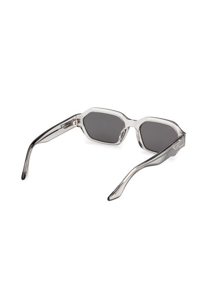 Gafas de sol rectangulares transparentes de color gris con varillas ligeramente curvadas y lentes de tintado oscuro, mostradas desde una vista trasera en ángulo.