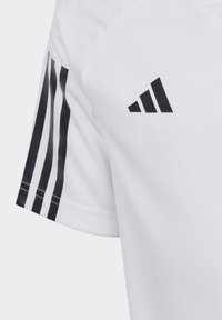 T-shirt de sport blanc avec un motif à trois rayures noires sur les manches et un logo noir sur la poitrine. Tissu lisse et léger.