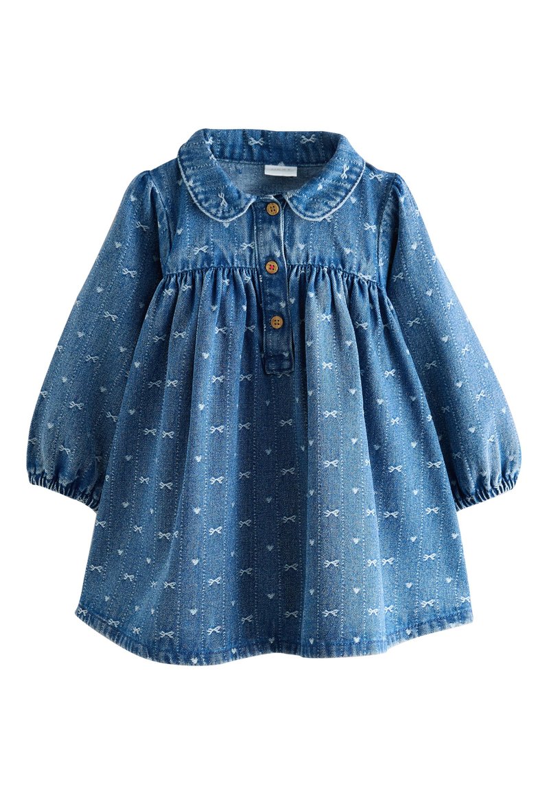Džínové šaty s golierom, dlhými nafúknutými rukávmi a zapínaním na gombíky. Vyrobené z modrej látky s bielymi vzormi mašlí a nariaseným pásom.