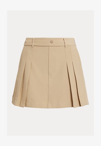 Μπεζ μίνι φούστα με πιέτες, θηλιές για ζώνη και κλείσιμο με κουμπιά μπροστά.