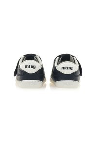 Zapatilla de deporte azul marino oscuro con un talón y suela blanca, que cuenta con cierre de velcro, una textura suave y el logotipo "mtng." grabado en la parte trasera.
