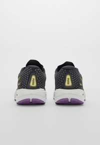 Chaussures de sport noires et grises avec un dessus en mesh, comportant des accents jaunes et un design à motifs. Semelle intermédiaire blanche avec une semelle extérieure violette.