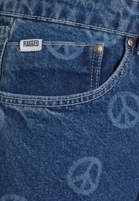 Jeans de denim em azul escuro com padrão de sinal de paz, apresentando um rótulo branco "RAGGED", ferragens prateadas e costura em contraste.