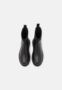 Czarne skórzane botki za kostkę z elastycznymi panelami bocznymi, zaokrąglonym noskiem i teksturowanym czarnym wykończeniem wnętrza. Szwowe detale wokół podeszwy.