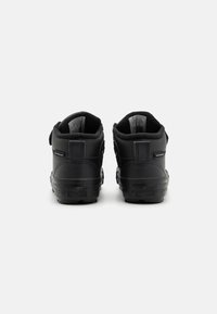 Černé kožené tenisky s vysokým designem, polstrovaným límcem a suchým zipem. Mají texturovaný povrch a gumovou podrážku s logem.