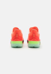 Helle orange Laufschuhe mit strukturiertem Obermaterial, gepolstertem Fersenbereich und einer verblassten grünen Außensohle. Verfügt über Logo-Akzente an der Ferse.